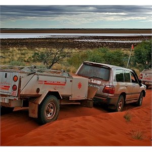 Driving through a dusty desert with a camper trailer