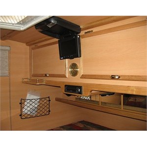 Inside a teardrop camper showing storage compartments and TV