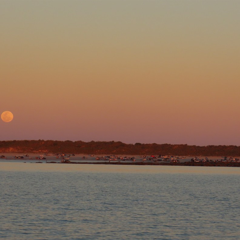 The Moon begins to rise over the carpark on the beach