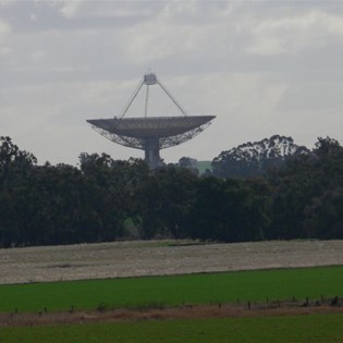 Parkes Radio Telescope seen across wet green paddocks.
