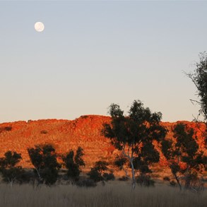 The sun on the hill behind with the moon still setting