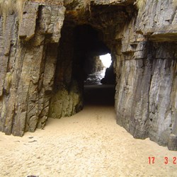 Cave at the bottom of a ravine, the far end opens out to the sea