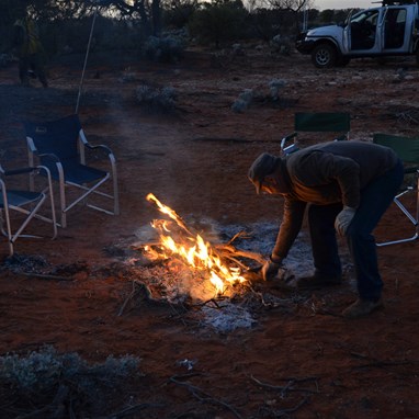 Larry adds another piece of timber to the morning fire