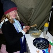 Chardae preparing a cake inside the tent and out of the weather