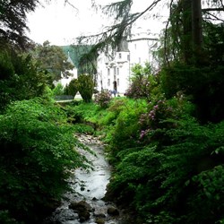 Blair Castle sits beside a little stream, surrounded by huge trees.