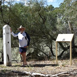 Stephen by the post and showing the history sign in the small clearing