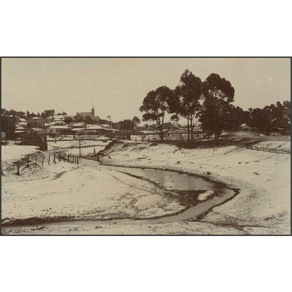 Snow covered ground with a town in the distance, 1910