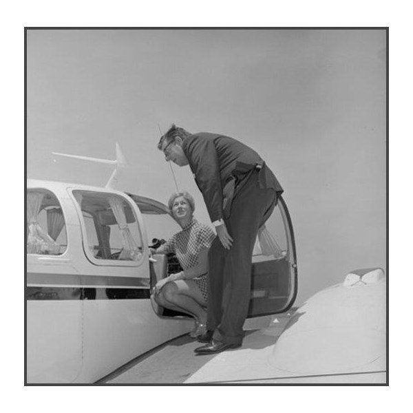 Robin Miller and man standing on wing of aircraft inspecting cockpit. 1969