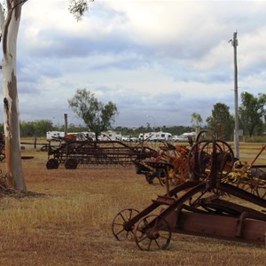 Old farm machinery with caravans in the background