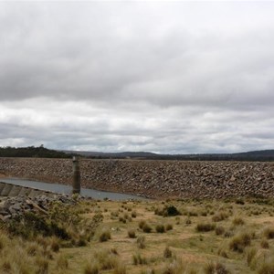 The multiple arch concrete dam can be seen in front of the rock wall